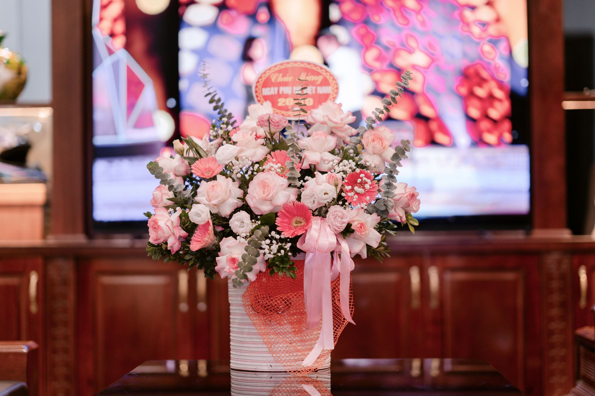 Beautiful floral bouquet with pink roses and daisies inside a well-lit room.