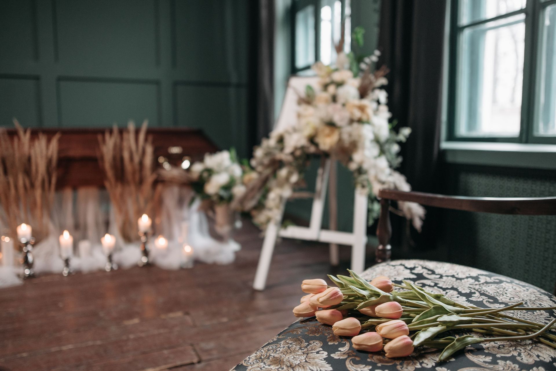 A serene funeral setting with candles and floral arrangements indoors, conveying loss and remembrance.