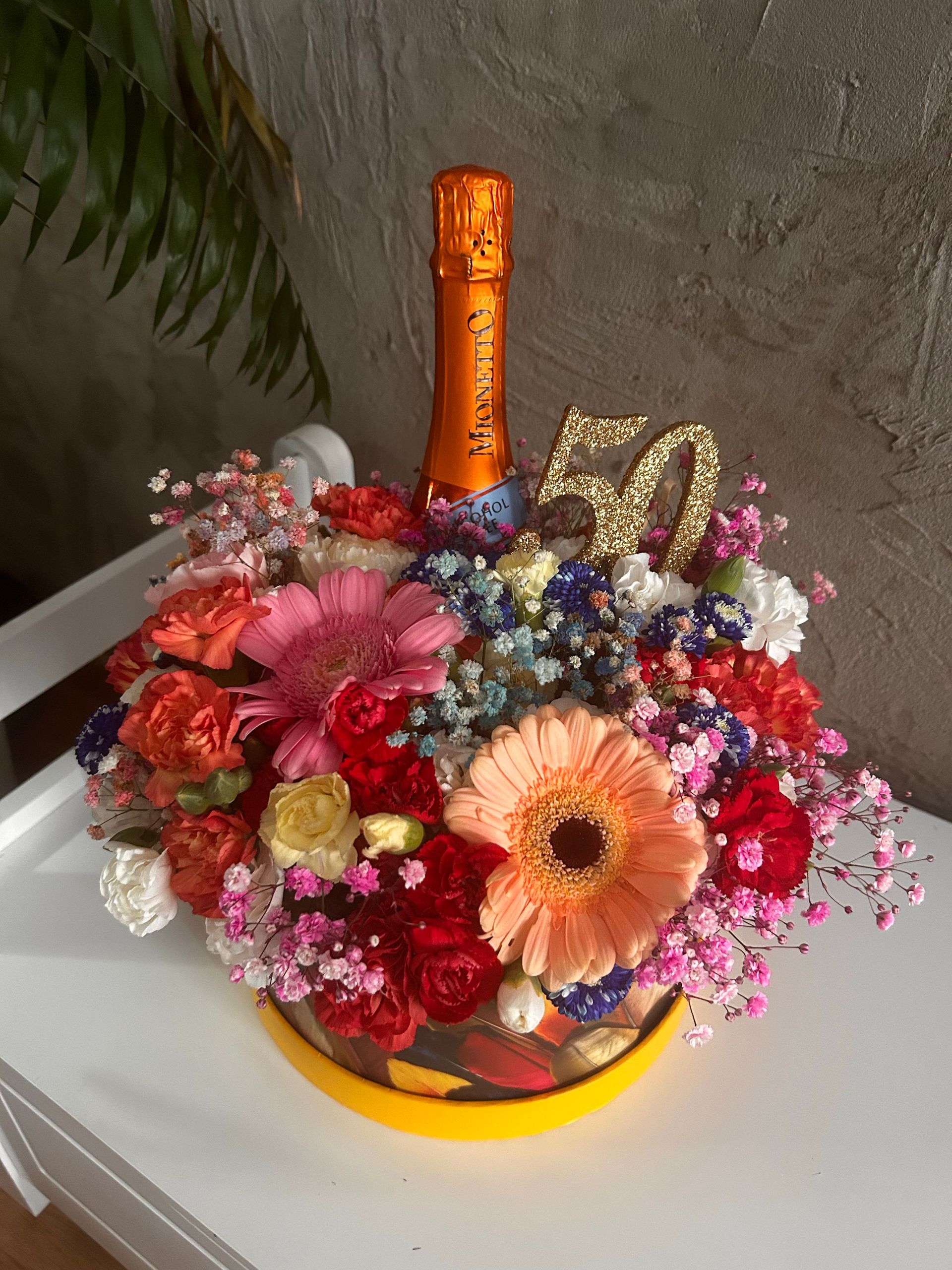 Vibrant flower arrangement with champagne celebrating a 50th birthday. Perfect gift idea.